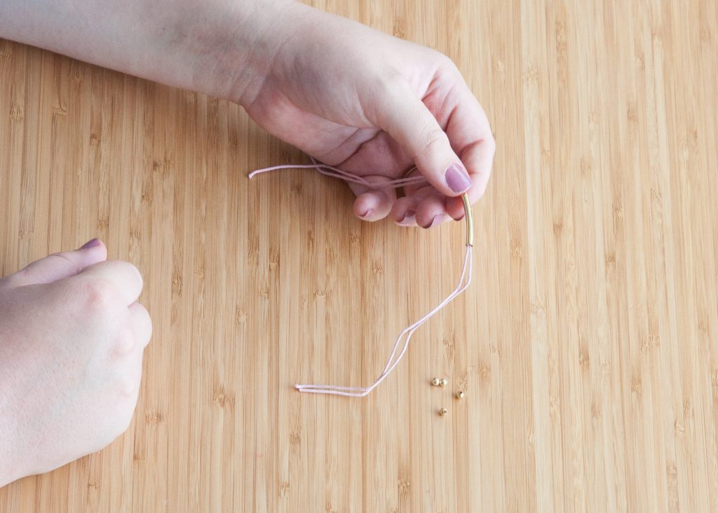 3 Easy DIY Bracelets You'll Actually Want to Wear. Image Description: Two hands beading a bracelet.