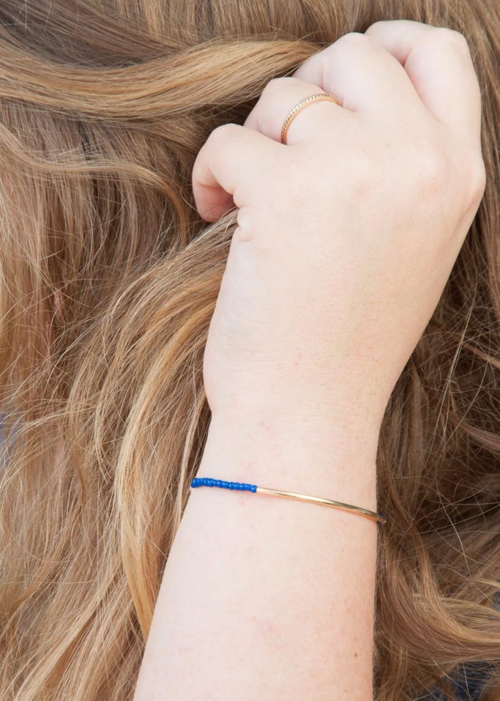 3 Easy DIY Bracelets You'll Actually Want to Wear. Image Descriotion: A hand modeling a blue and gold bracelet.
