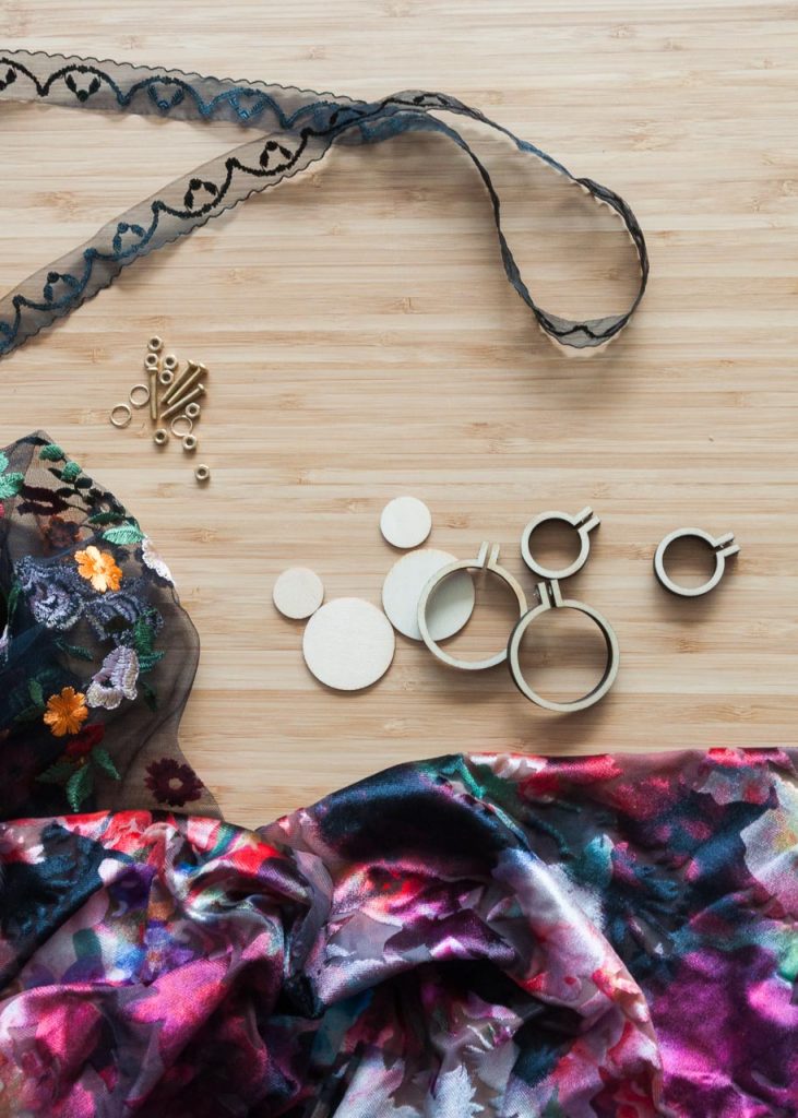 How to Make No-Sew Mini Embroidery Hoop Necklaces. Image Description: fabric and mini embroidery hoops on a desk.